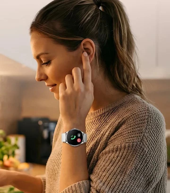 Frau nimmt beim Kochen in der Küche einen Anruf an ihrer Grace Smartwatch an